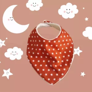 Bavoir forme bandana. Un côté en tissu coton couleur rouille avec des étoiles blanches et un côté en éponge velours écru.